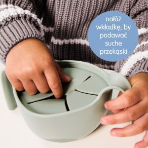 Dziecko w szaro białym sweterku w paski sięga do różowego pojemnika na przekąski b.box Miseczka 3w1. W niebieskim kółku znajduje się polski tekst: nałóż wkładkę, by podawać suche przekąski.